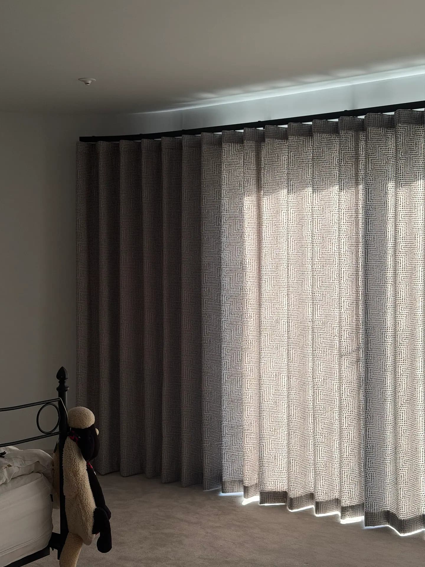 Floor-length layered curtains on a curved bedroom track