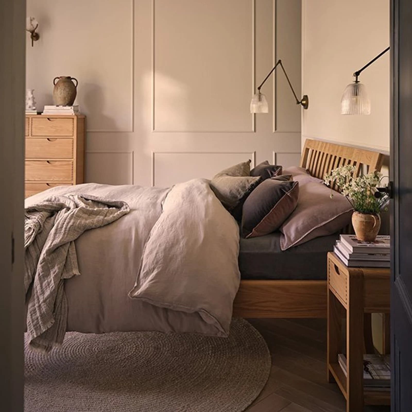 Ercol light wood bed with slatted headboard, bedside table and tall chest in a calm bedroom
