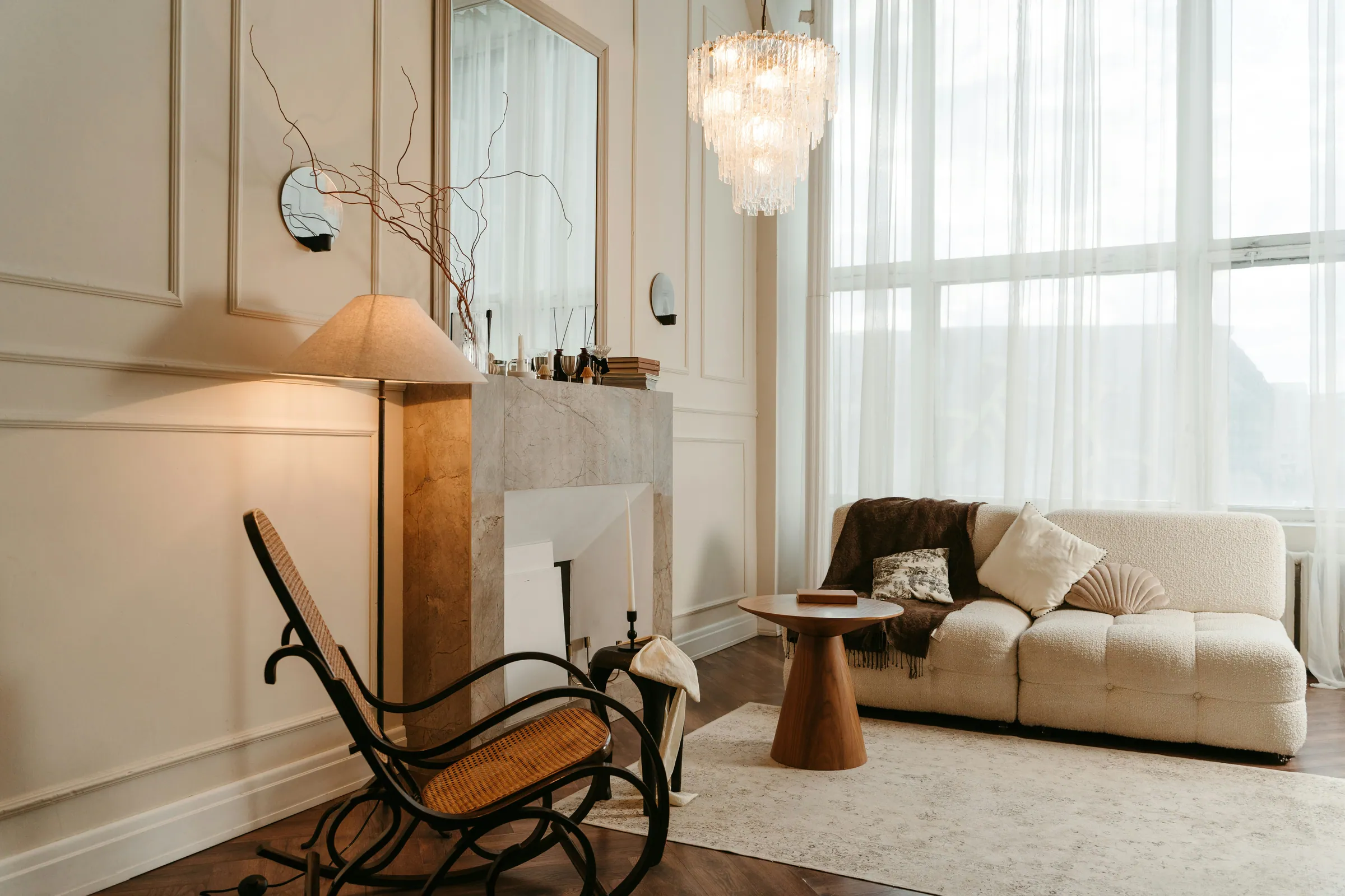 Bright living room with a cream bouclé sofa, marble fireplace, and dark herringbone floors