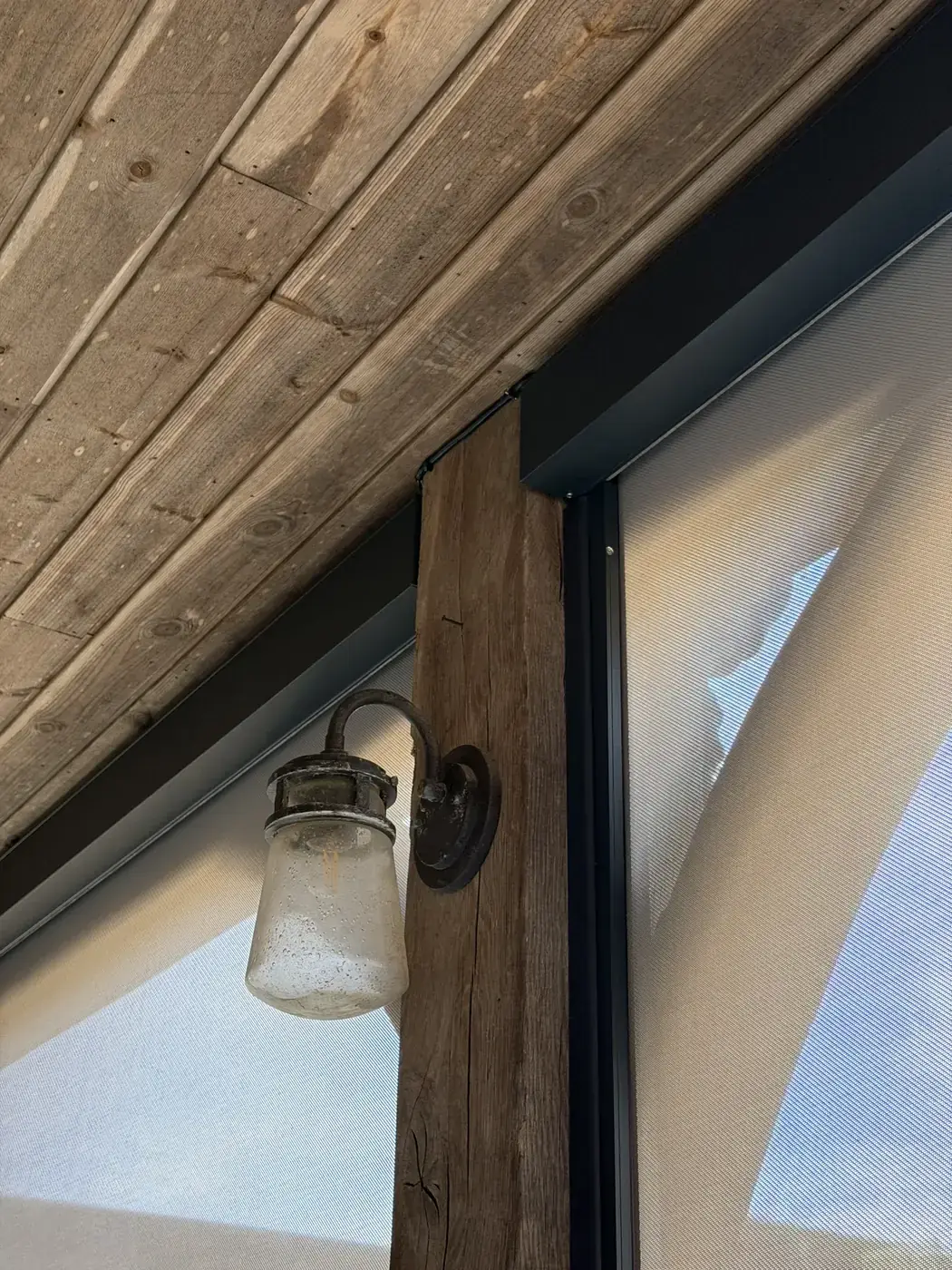 Close-up of Luxaflex external screen blind cassette, side guides and mesh fabric on timber beams