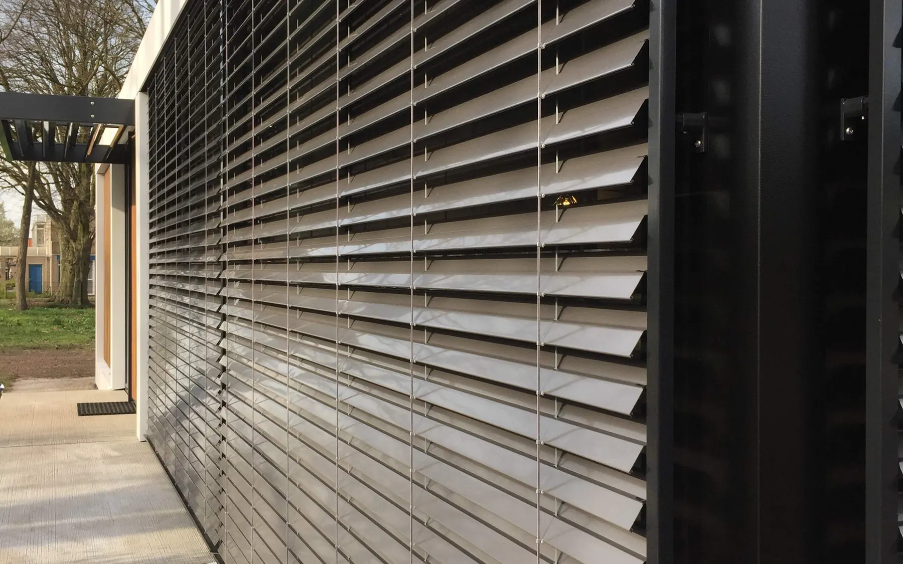External venetian blinds with tilted aluminium slats on the outside of a building