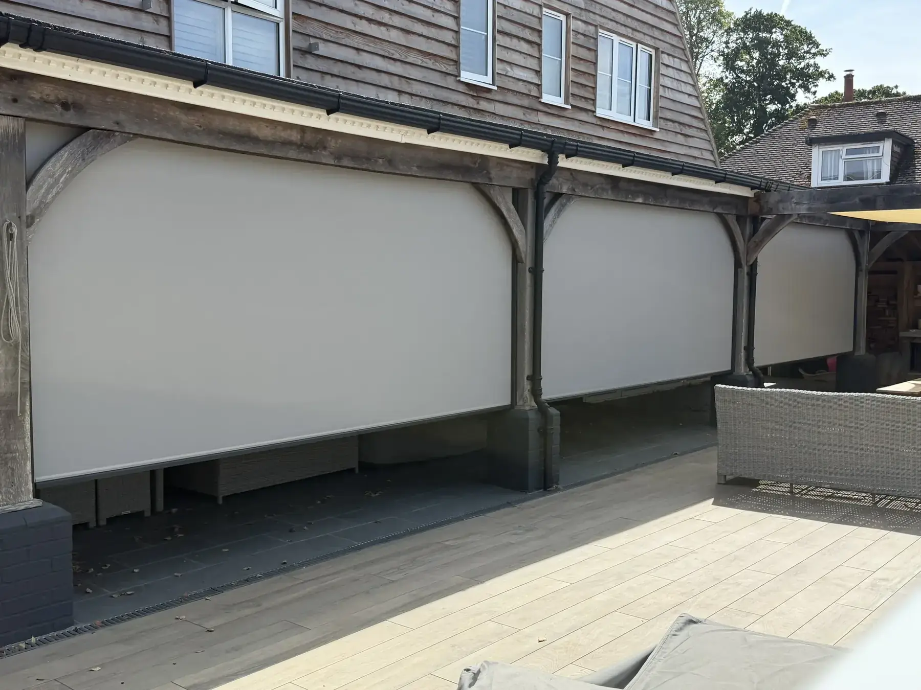 Three Luxaflex external screen blinds fully dropped on a timber-framed veranda